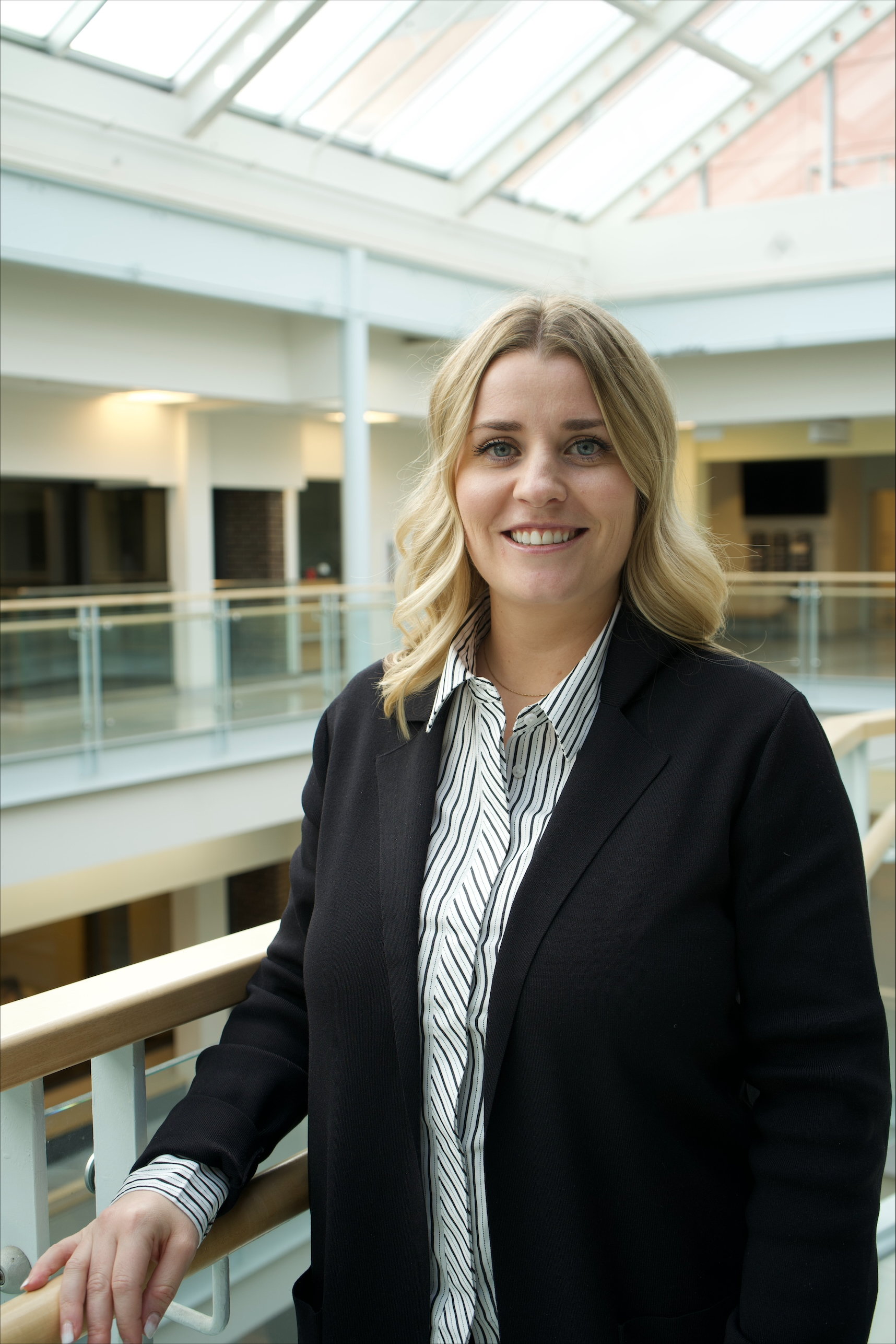 Ashleigh is a white woman with long blonde hair. She wears a collared shirt and black blazer.