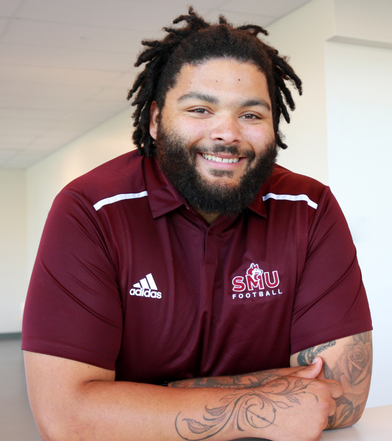 Che is a Black man with long hair and a beard