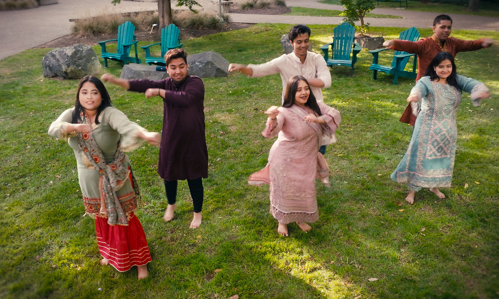 Students in traditional Bengali clothing perform a dance on campus grounds